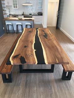 a wooden table sitting in the middle of a living room next to a kitchen area