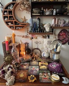 a wooden table topped with lots of cards and candles next to shelves filled with figurines