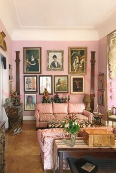 a living room with pink walls and pictures on the wall