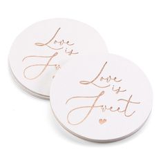 two white coasters with gold foil lettering on them