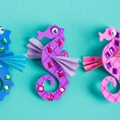 three paper seahorses on a blue background