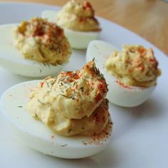 deviled eggs with seasoning sprinkled on them sitting on a white plate