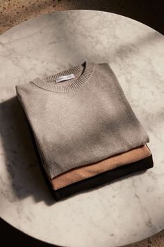 two sweaters are sitting on a marble table