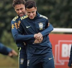 two soccer players are hugging each other while they're going to the field for practice