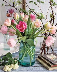 a vase filled with pink and white flowers on top of a table next to books