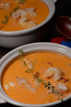 two white bowls filled with soup and garnished with shrimp on the top one