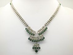 Hello and welcome to my shop. I am offering to you this very fine classic center tassel drop design vintage 1950's / 60's period diamante necklace. As you will see in the pictures the piece is made using silvertone metal for the mount and is set with sparkly green and clear white mixed size diamante stones. The clasp is an old hook through ring type in good working condition. The sparkly green and clear white diamante stone necklace is in excellent used vintage condition with no or only very slight age related surface wear as shown. Please see my five pictures as they are part of my description of the  details of the colours, design and general condition of this fine piece of vintage jewelry. Thanks The total length of the necklace with clasp and extension is :- 46 cms.  18 inches approx. Green Rhinestone Necklace For Formal Occasions, Green Costume Jewelry Necklace, Formal Green Rhinestone Necklace, Silver Crystal Necklaces With Sparkling Stones, Costume Jewelry, Vintage Metal Rhinestone Necklace With Jewels, Vintage Metal Rhinestone Necklace With Sparkling Stones, Vintage Metal Rhinestone Necklace, Drop Design, Clear White