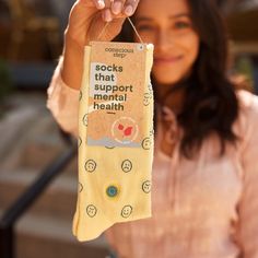 a woman holding up a sock that says socks that support mental health