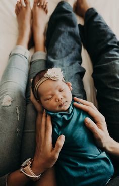 a woman holding a baby in her lap while laying on the floor next to two other people