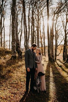 a couple standing next to each other in the woods