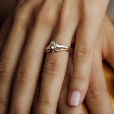 a woman's hand with a diamond ring on top of her finger and an engagement band