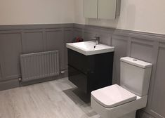 a white toilet sitting next to a sink in a bathroom on top of a hard wood floor