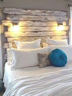 a bed with white linens and pillows on it in front of a window that has wooden headboard