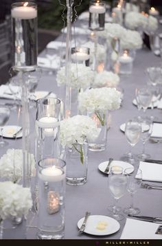 the table is set with white flowers and candles