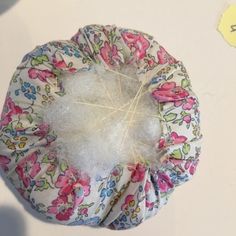 a close up of a flowered hat on top of a white table with scissors