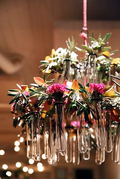 a chandelier with flowers and wine glasses hanging from it's centerpiece