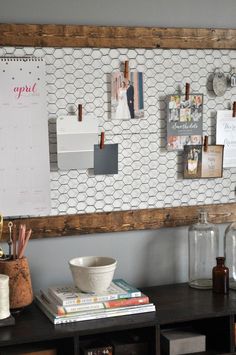 a wooden desk topped with lots of clutter and office supplies next to a wall mounted calendar