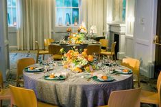 a table set with place settings and flowers on the centerpieces for an elegant dinner