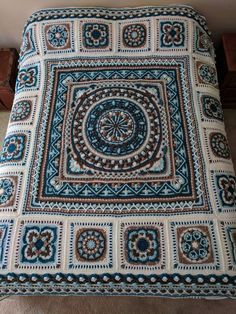 a blue and white crocheted blanket sitting on top of a bed