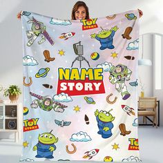 a woman holding up a personalized blanket with cartoon characters all over it and the words name story