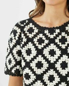 a woman is wearing a black and white crochet top with an openwork pattern