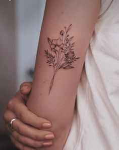 a woman's arm with a flower tattoo on the left side of her arm