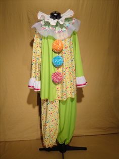 a green and white clown costume on a mannequin's head with pom - poms