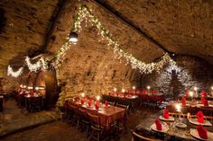 a dimly lit dining room with red and white tablecloths, candles and wine barrels