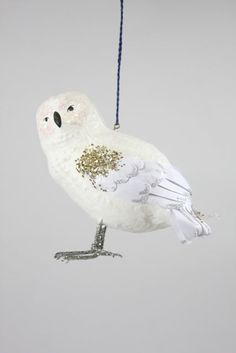 a white bird ornament hanging from a blue string on a gray background with gold flecks