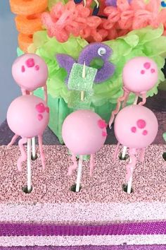 pink flamingo cake pops are arranged in front of an arrangement of flowers and grass