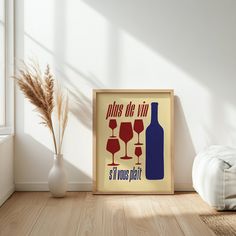 there is a framed poster on the floor next to a vase with some wine glasses