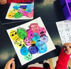 two children are drawing faces on paper with colored crayons