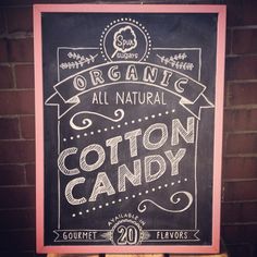 a sign advertising cotton candy in front of a brick wall with the words organic all natural written on it