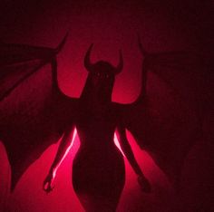 the silhouette of a woman in a dark room with red light shining on her body