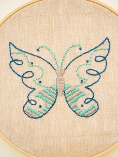 an embroidered butterfly is shown on the back of a piece of linen with blue thread