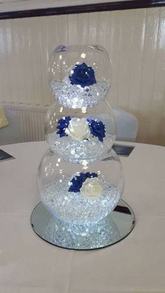 three clear vases filled with flowers on top of a white tablecloth covered table