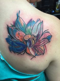 the back of a woman's shoulder with a colorful flower tattoo on her left side