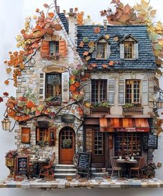 a house made out of paper with autumn leaves on the roof and windows, sitting in front of a white wall