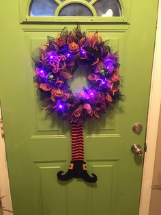 a green door with a purple and black wreath hanging on it's front door