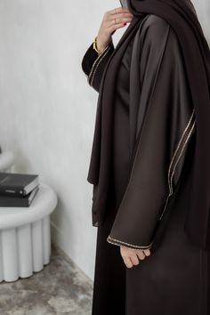 This chocolate brown abaya has been decorated with intricate handwork along the sleeves which follows round the back of the abaya. This 3 piece abaya set is the perfect choice for all occasions. It has been manufactured in luxury fabric which has a satin feel. The abaya slip has a long zip along the centre front, making it breastfeeding friendly. The cut of the abaya is slightly oversized, giving it a beautiful flow when you walk. Indulge in the rich allure of our Chocolate Brown Abaya, a timele Modest Capsule Wardrobe, Brown Abaya, Abaya Shop, Black Abaya, Luxury Fabric, Brown Line, Hijabi Outfits Casual, Abaya Designs, Hijabi Outfits