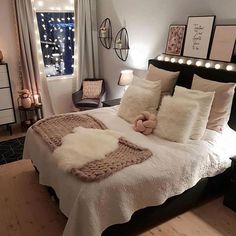 a bed with white blankets and pillows on top of it in a bedroom next to a window