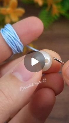 a person holding a thread and needle in their hand