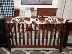 a brown and white cow print baby crib bedding set in a nursery room