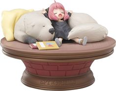 a figurine laying on top of a bed next to a stuffed animal bear