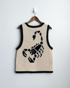 a white and black sweater with a horse on it hanging from a wooden hanger