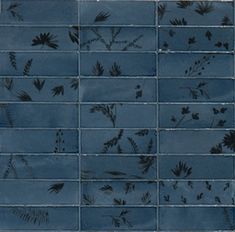 a blue tiled wall with black and white flowers on it