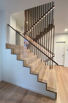 a wooden stair case in a home with white walls and wood flooring on both sides