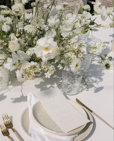 a table set with white flowers and silverware