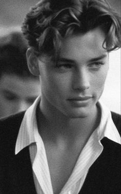 black and white photograph of a young man with curly hair wearing a shirt, looking to the side