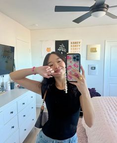 a woman taking a selfie in her bedroom with the ceiling fan hanging above her